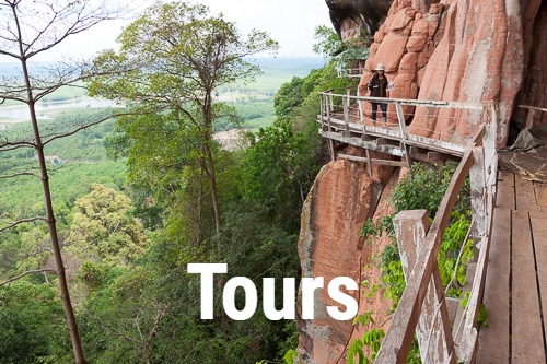 woman walking on cliff-side pathway at Wat Phu Tok